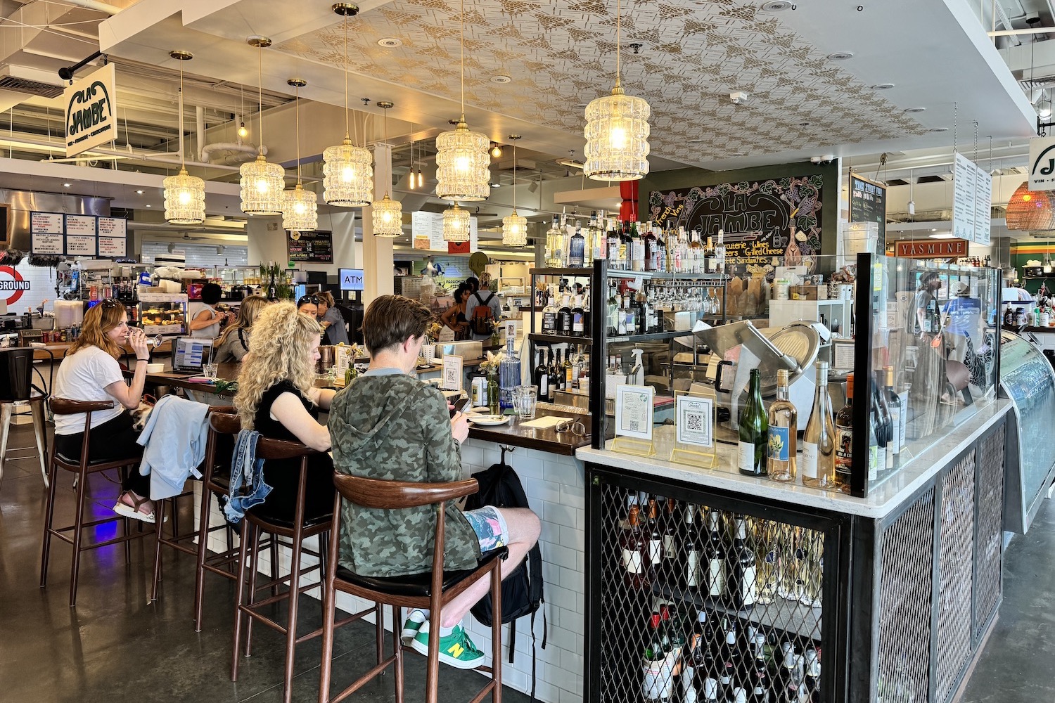 people sitting around a wine bar in a food hall