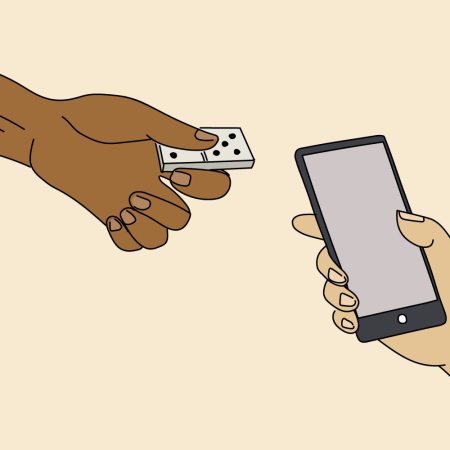 The hand of a Gen X man holding a domino and a Gen Z man holding a smartphone. We take a look at an intergenerational friendship and see how they bridge the widening generational gap.