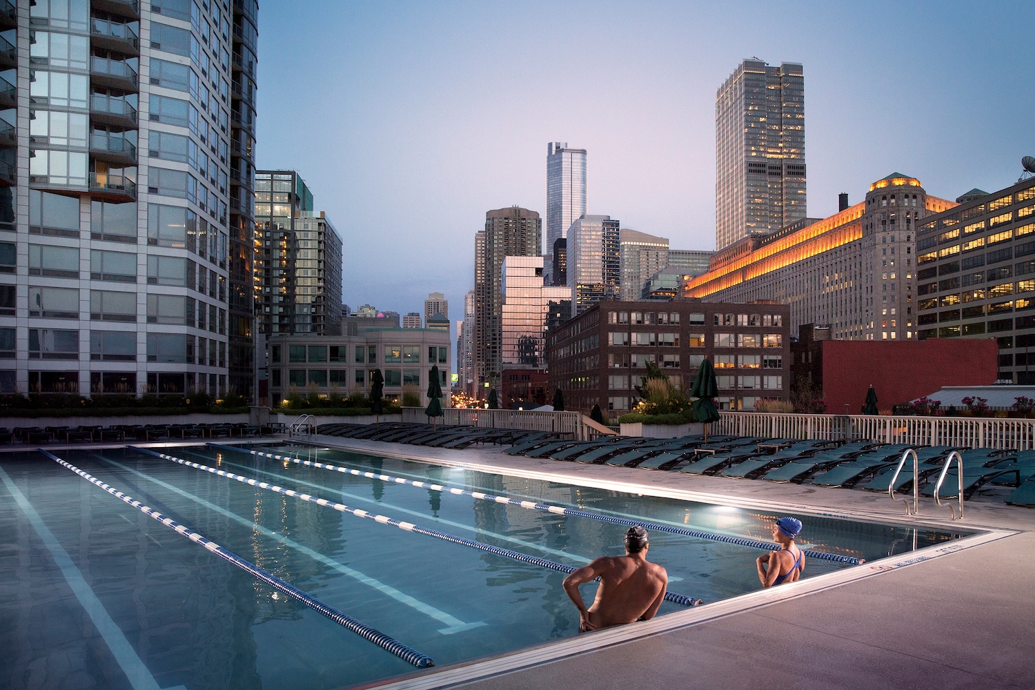 man and woman at edge of pool, buildings and skylines