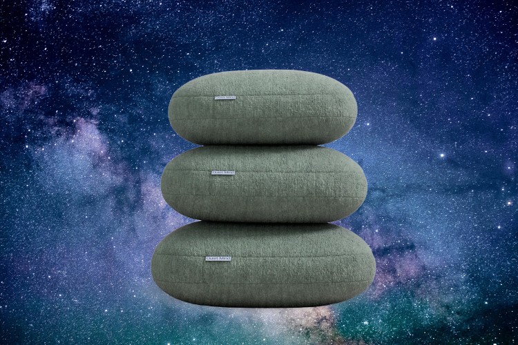 A pile of weighted pillows from Quiet Mind against a soothing cosmic background. Here's our review of their Original Weighted Pillow.