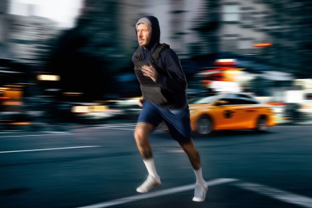 A man with a weighted vest jogs through a blurry cityscape. Here's why you should incorporate weighted vests into your workouts.