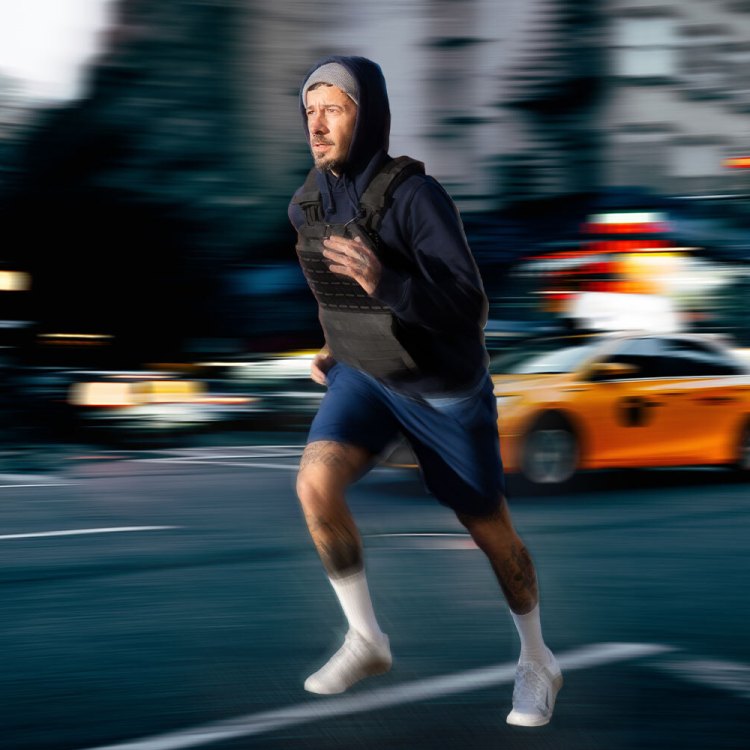A man with a weighted vest jogs through a blurry cityscape. Here's why you should incorporate weighted vests into your workouts.