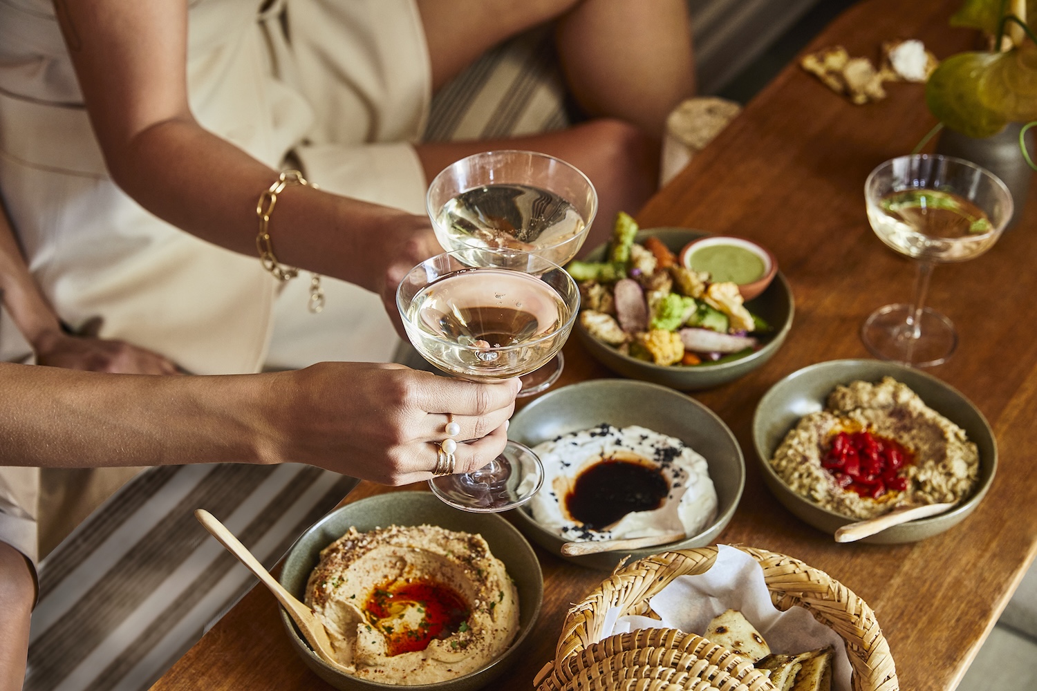 plates of hummus, woman holding two glasses of wine
