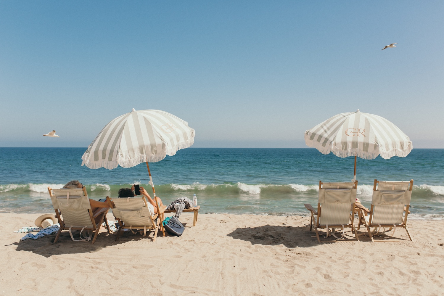 two beach umbrellas with beach chairs, sand, ocean