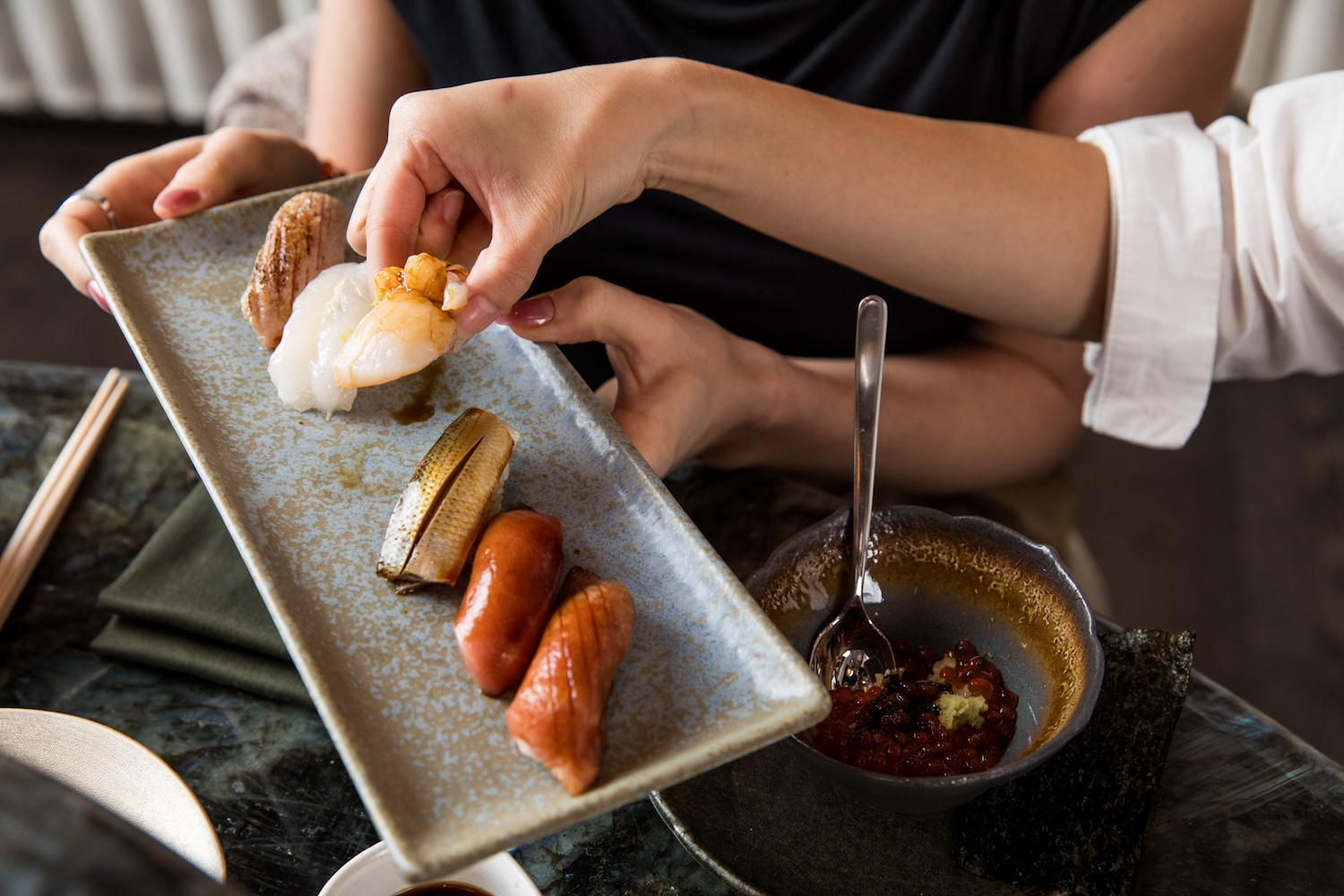 woman holding sushi, plate of nigiri