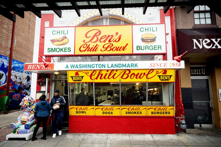the outside of ben's chili bowl in washington dc with a couple people standing in front