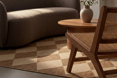 lifestyle image focused on harlequin patterned rug with a couch, chair and coffee table sitting on top