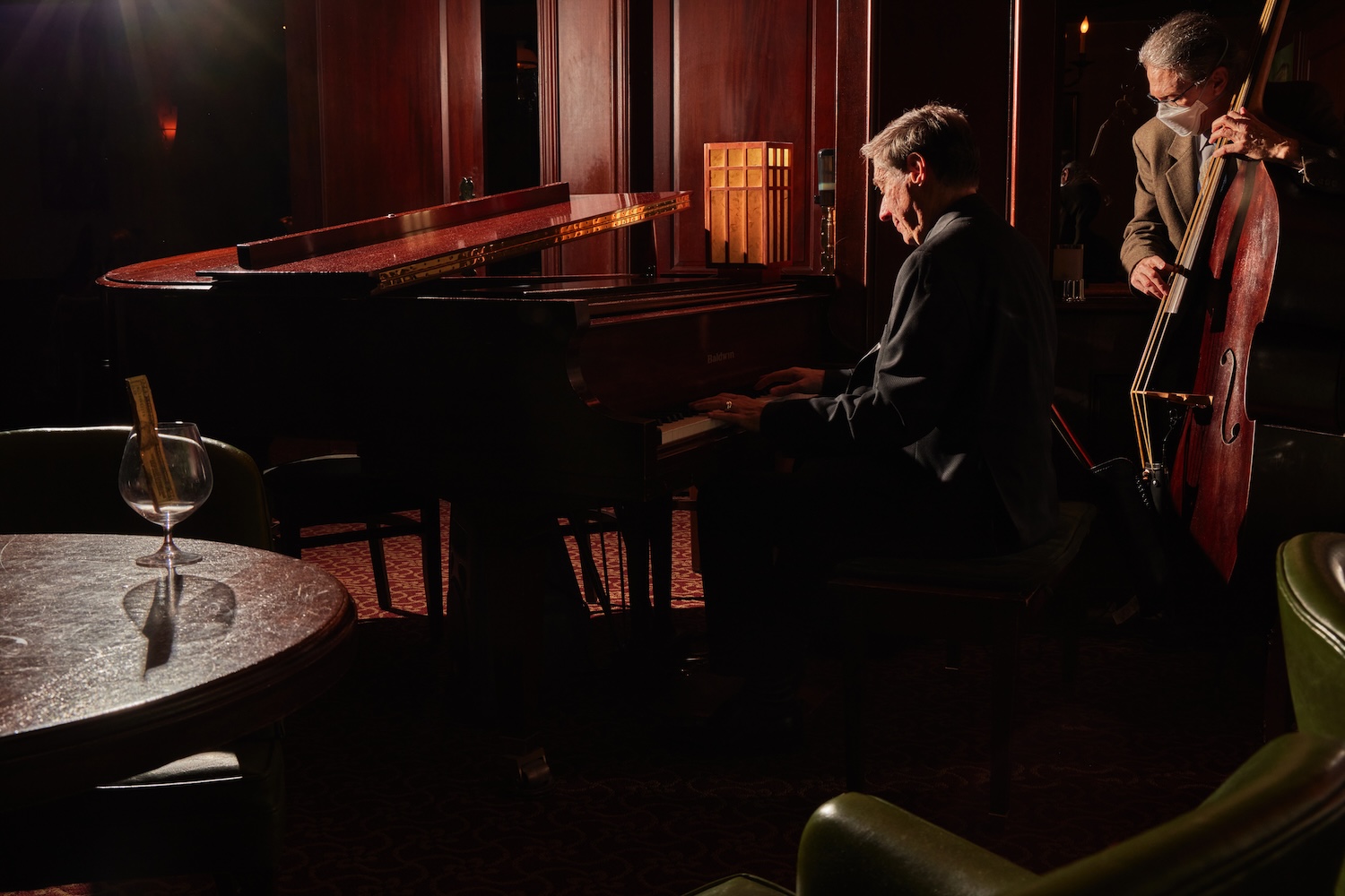 man playing piano in a suit in dim lit room