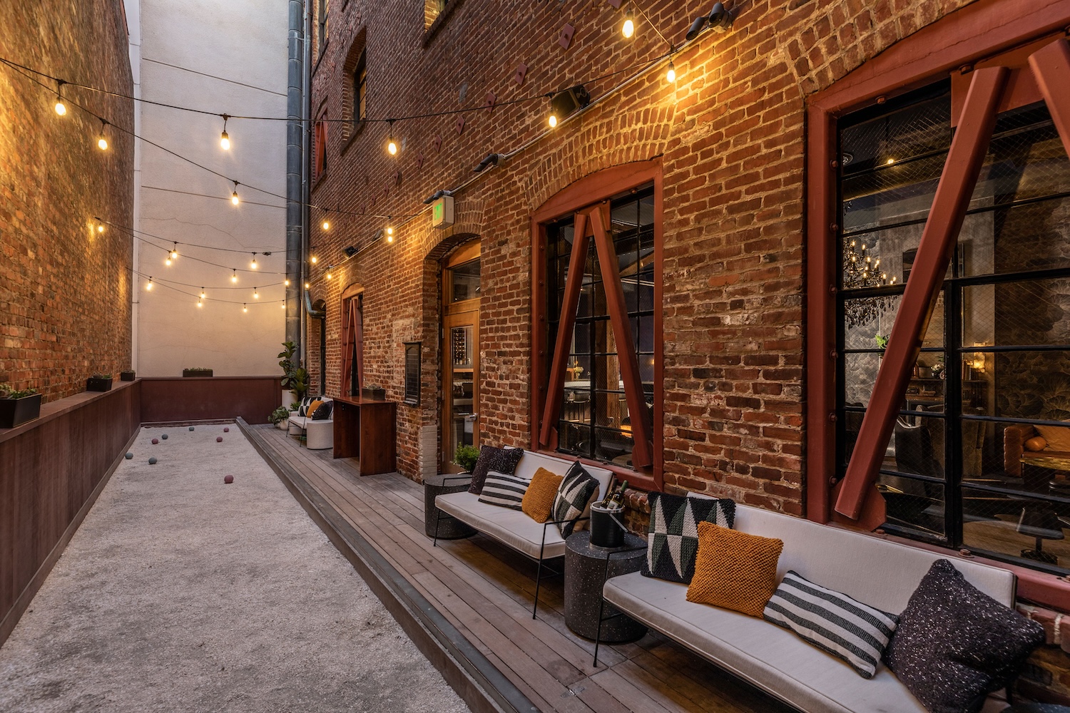 couches with throw pillows, windows, fairy lights, exposed brick