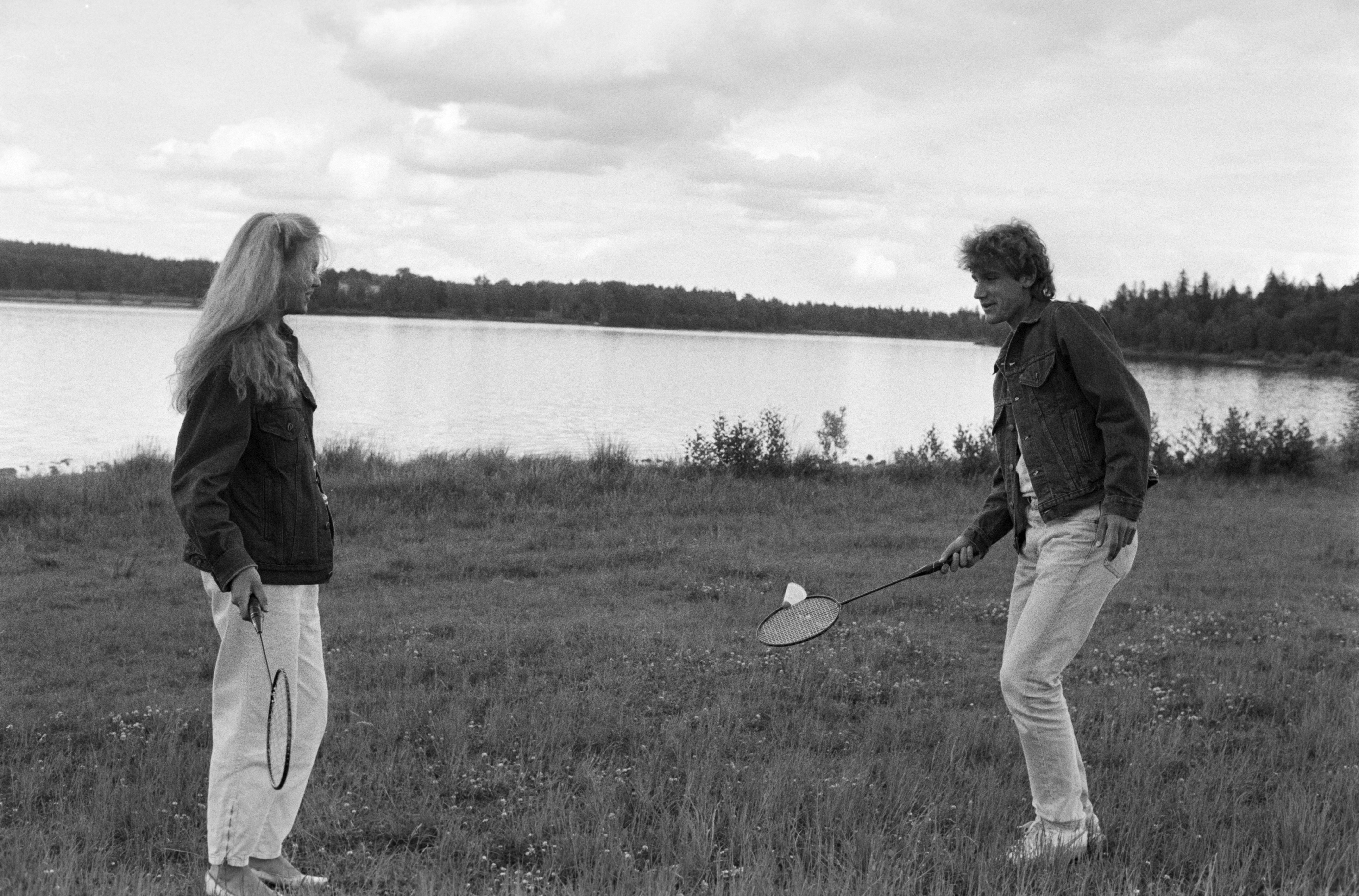 A man and woman playing with badminton equipment.