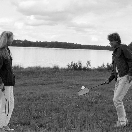 A man and woman playing with badminton equipment.