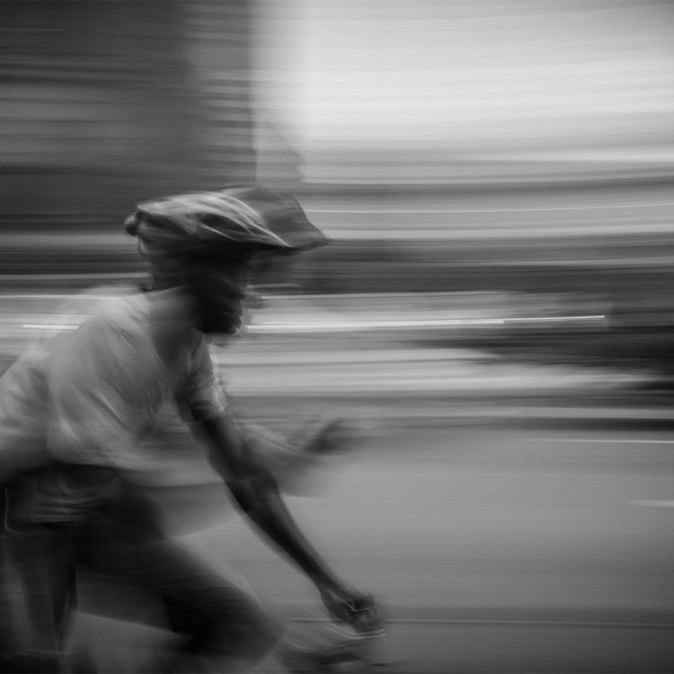 A man looking at his phone while riding a bike, black and white.