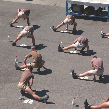A group of men stretching on the ground. The frog pose is an ideal yoga pose and stretch for people who sit all day.