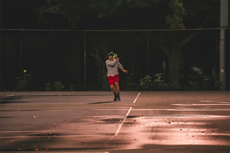 A man running around on a tennis court.