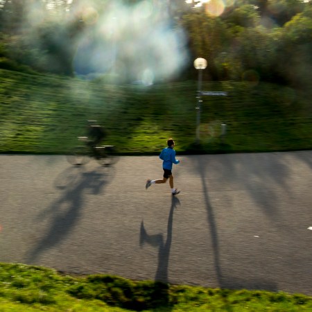 A man running through a park as the sun sets.