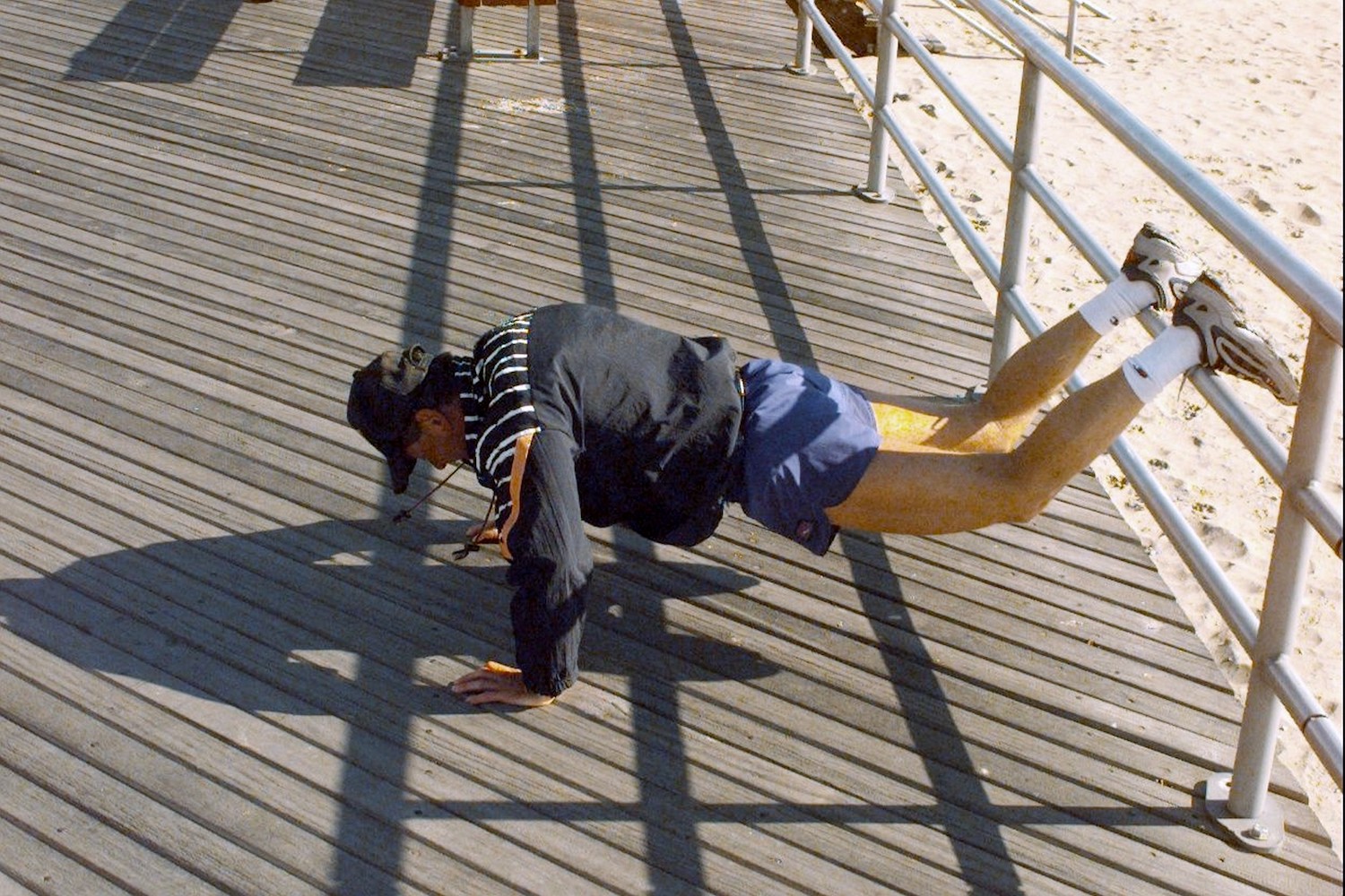 A man doing push-ups on the boardwalk.