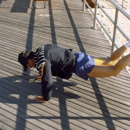 A man doing push-ups on the boardwalk.