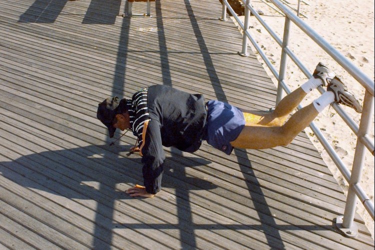 A man doing push-ups on the boardwalk.