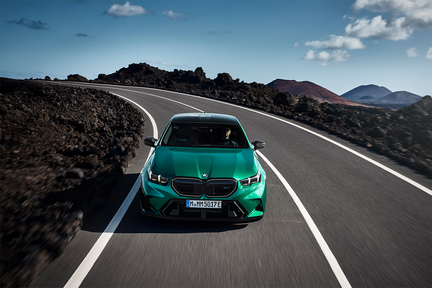 A 2025 BMW M5 in green driving down the road