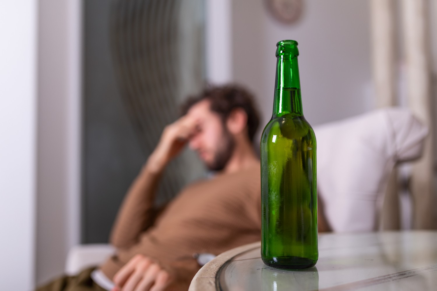Man slumped behind beer bottle