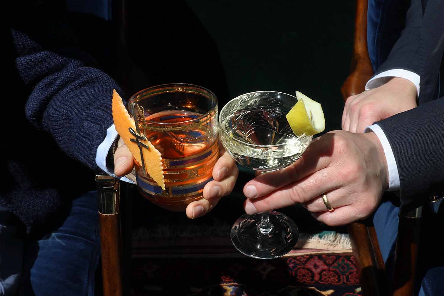 Two people cheers-ing and clinking glasses filled with booze