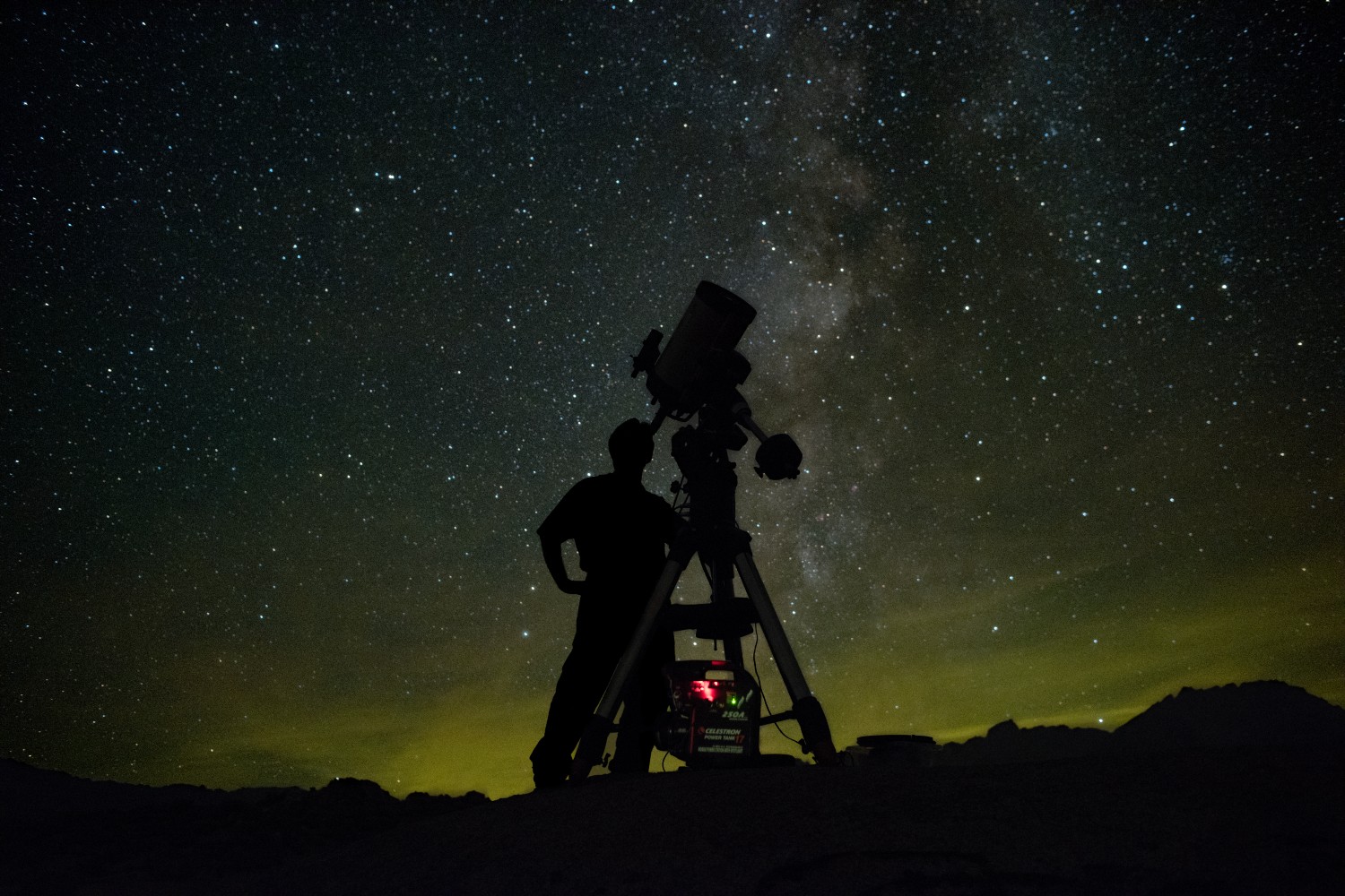 An astronomer using a telescope to look at the night sky