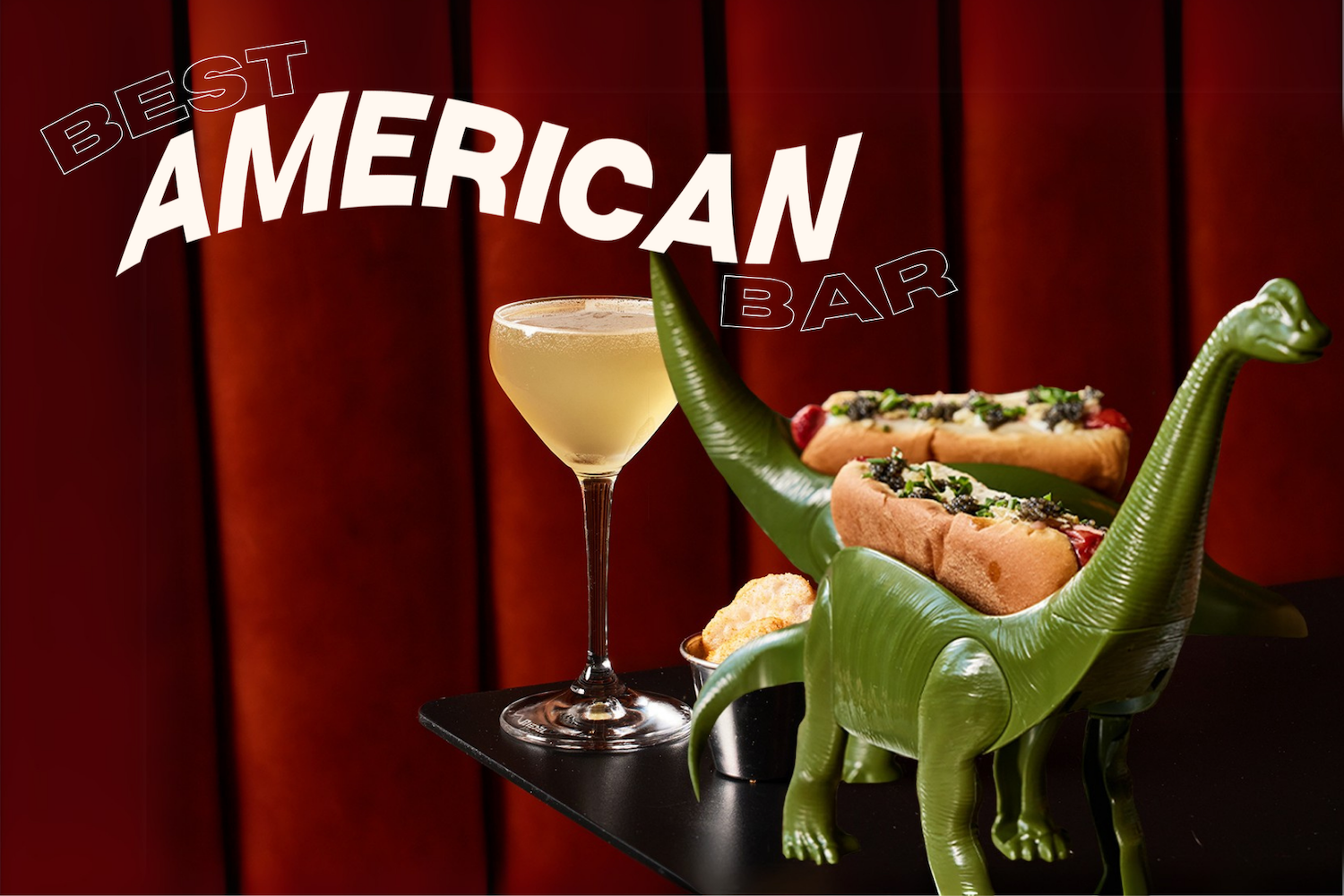 A cocktail from Yacht Club in Denver next to a dinosaur taco holder in front of a red velvet curtain
