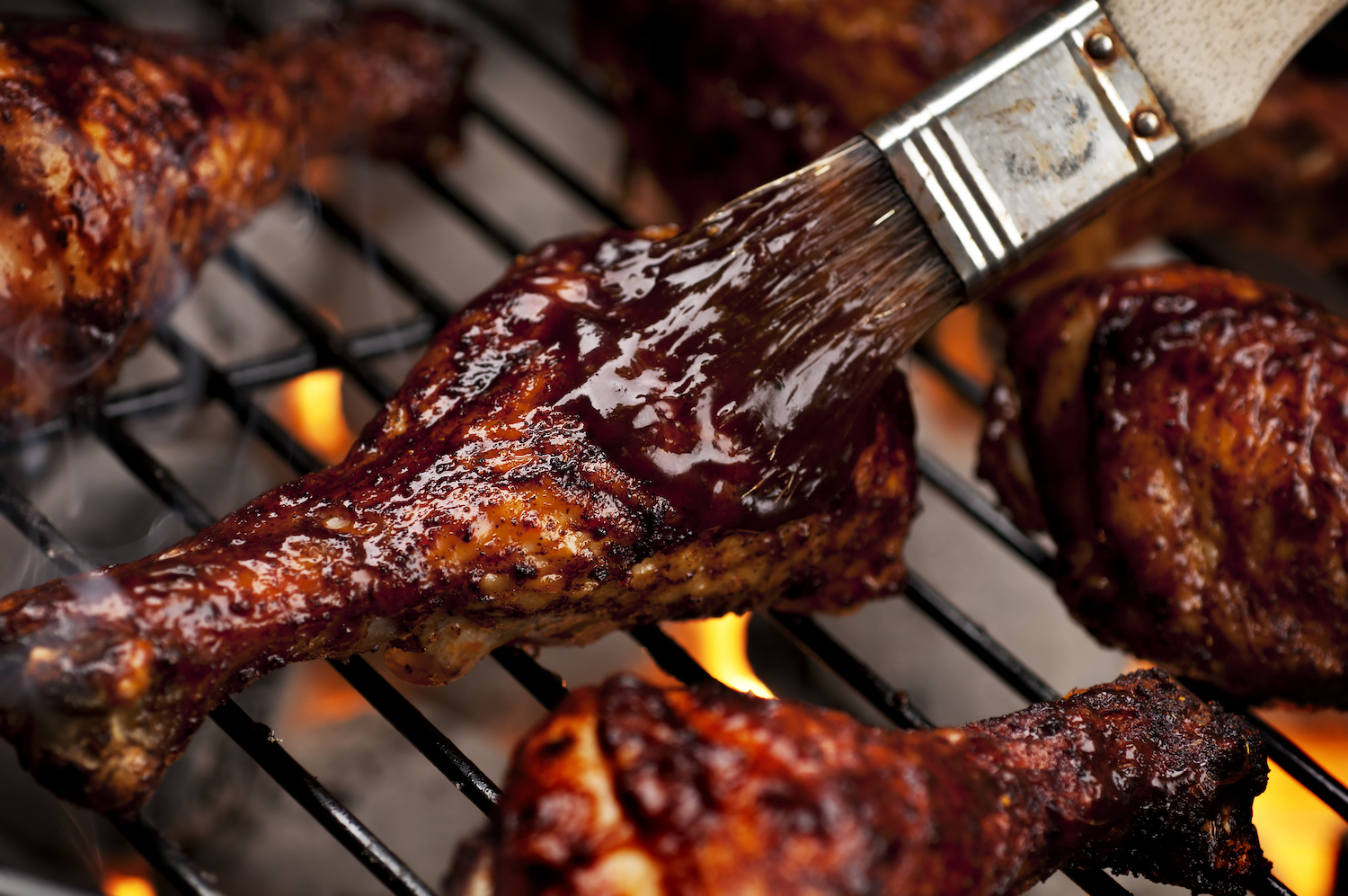 Chicken legs on the grill with barbecue sauce.