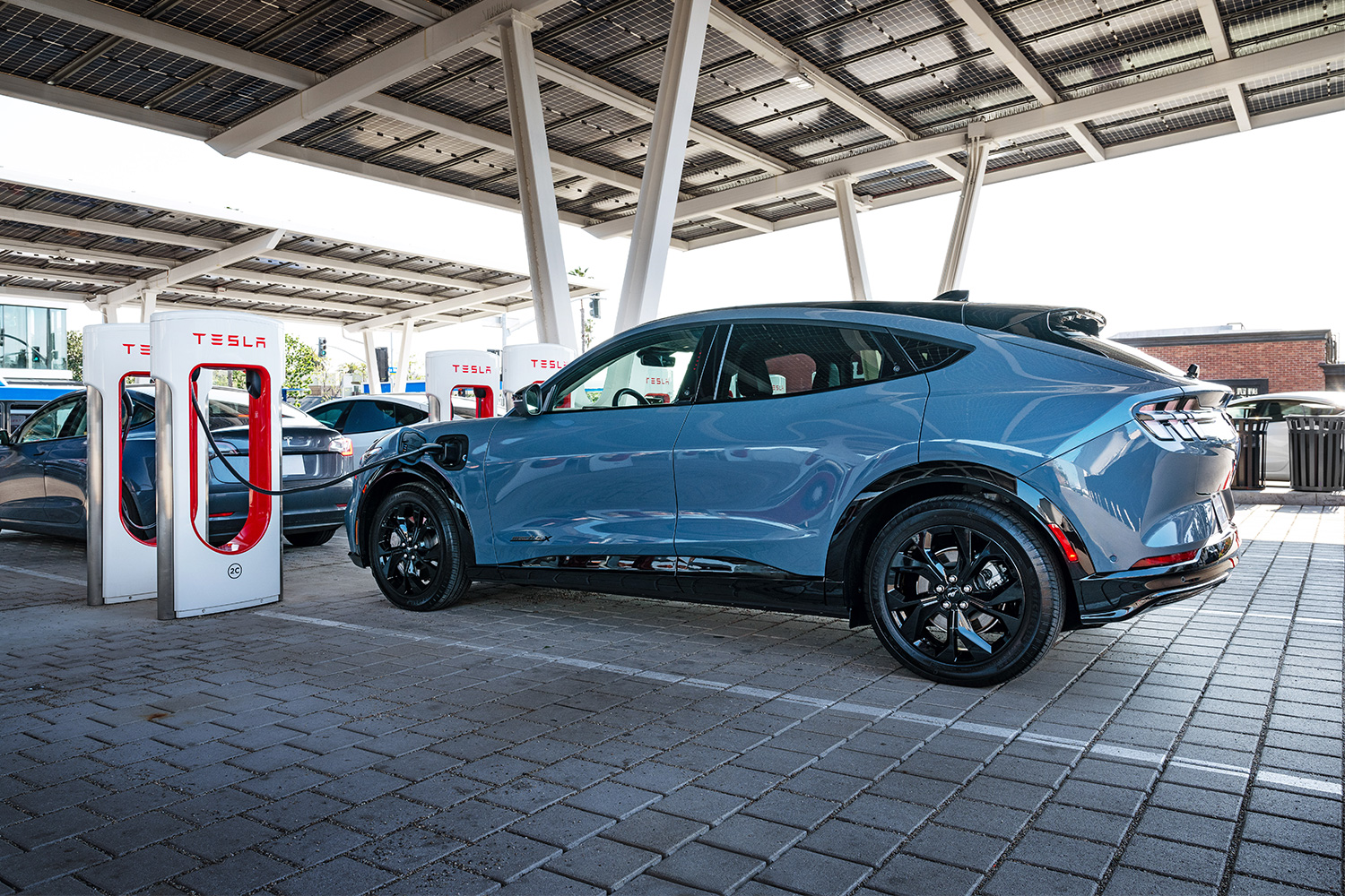 Ford Mustang Mach-E electric SUV charging at a Tesla Supercharger