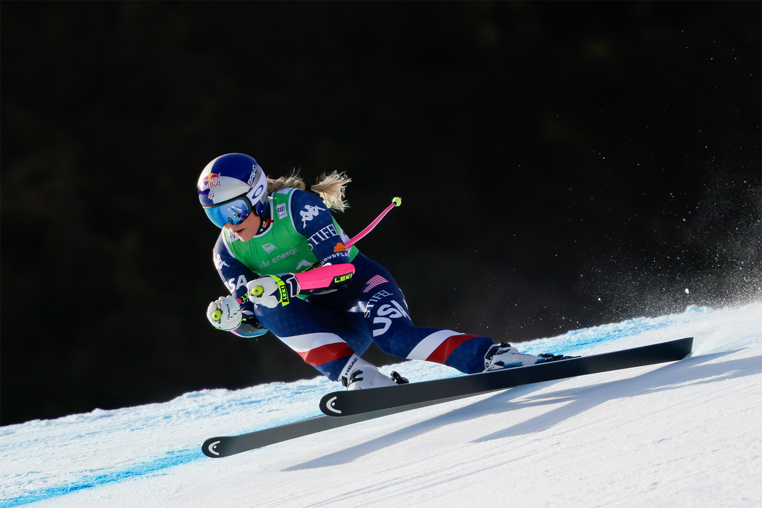 Lindsey Vonn skiing downhill at high speed, wearing Team USA gear, after returning to racing with a titanium knee.