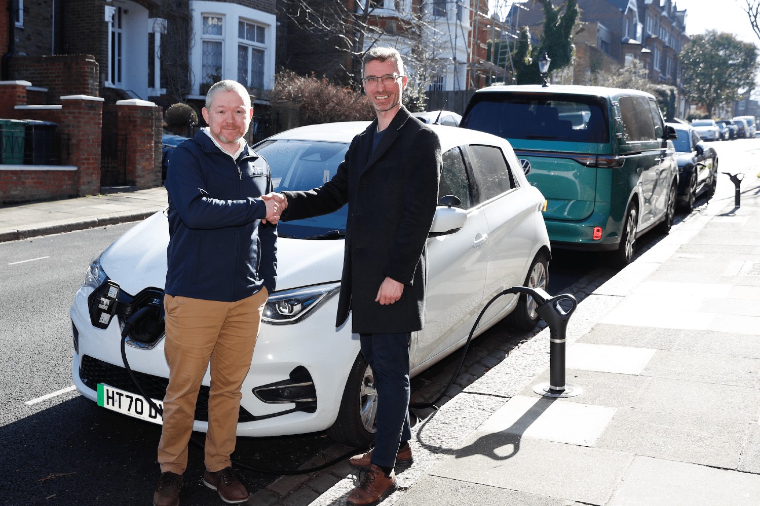 Camden Council and Trojan Energy representatives shaking hands with an EV charger behind them