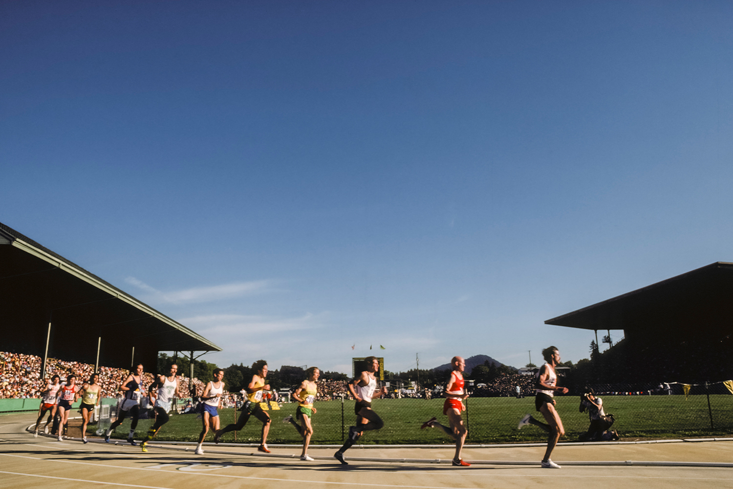 Runners competing in a track race on a sunny day, with packed grandstands. Here's why everyone should know their mile time, even if you're not a runner.