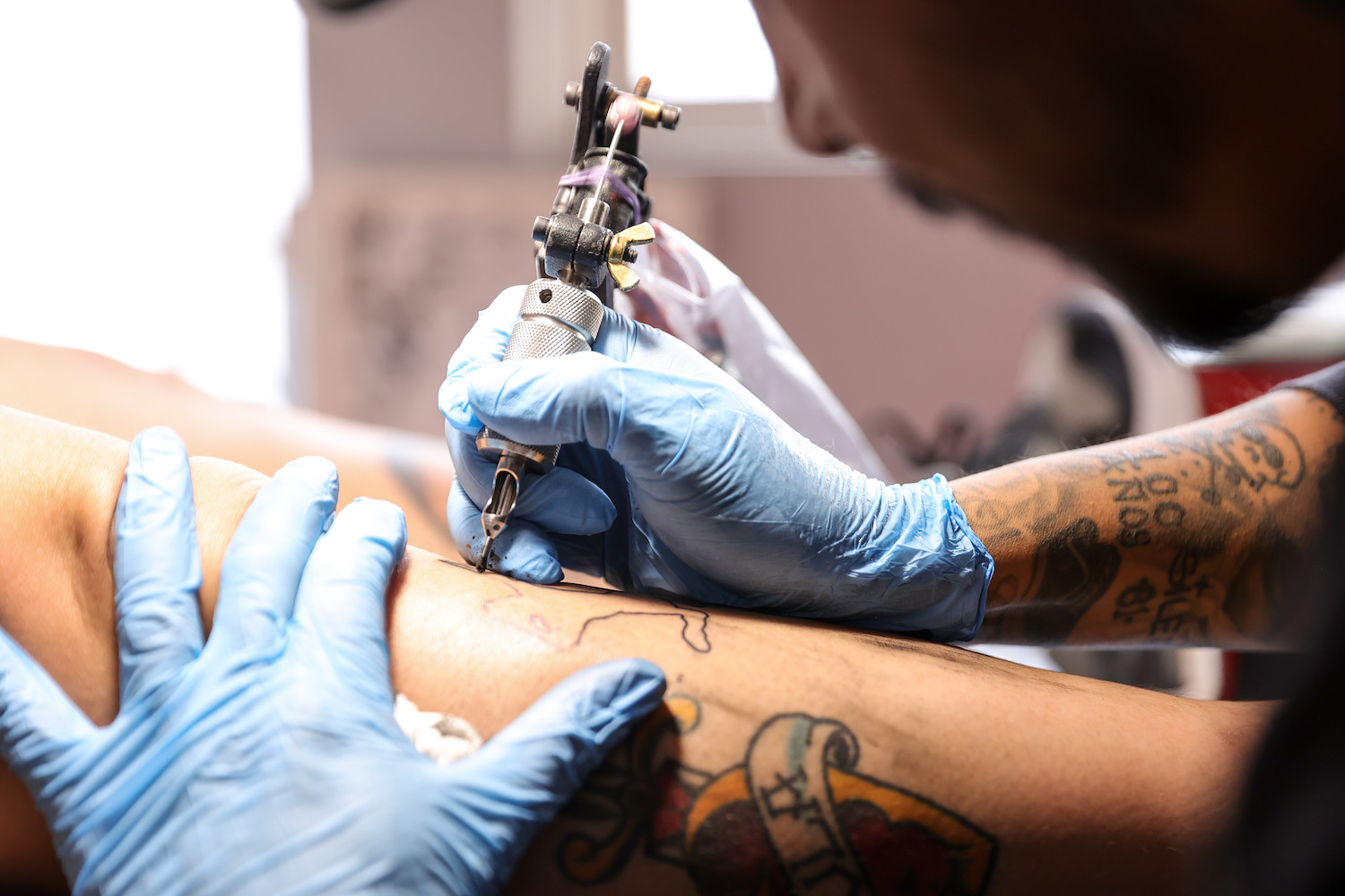 Israel Ortega tattooing a person's leg at a tattoo salon located in the Iztapalapa neighborhood