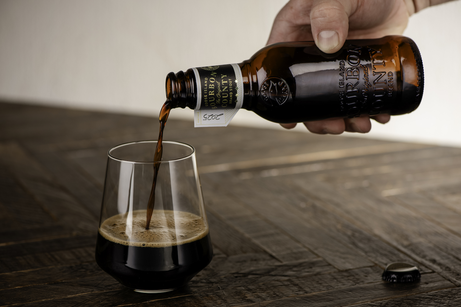 a hand pouring goose island bourbon county stout from a 10-ounce bottle