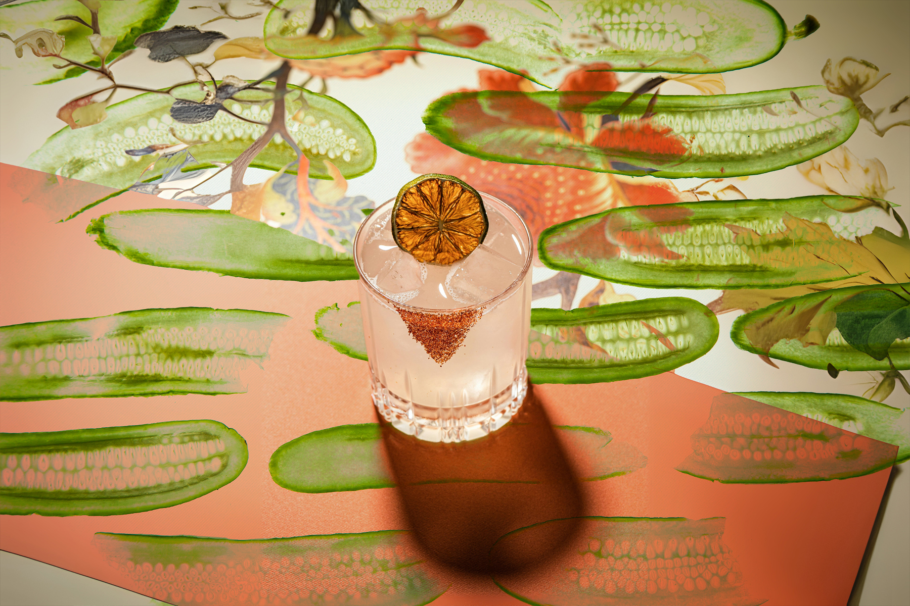 A margarita on a table covered with graphic images of pickles