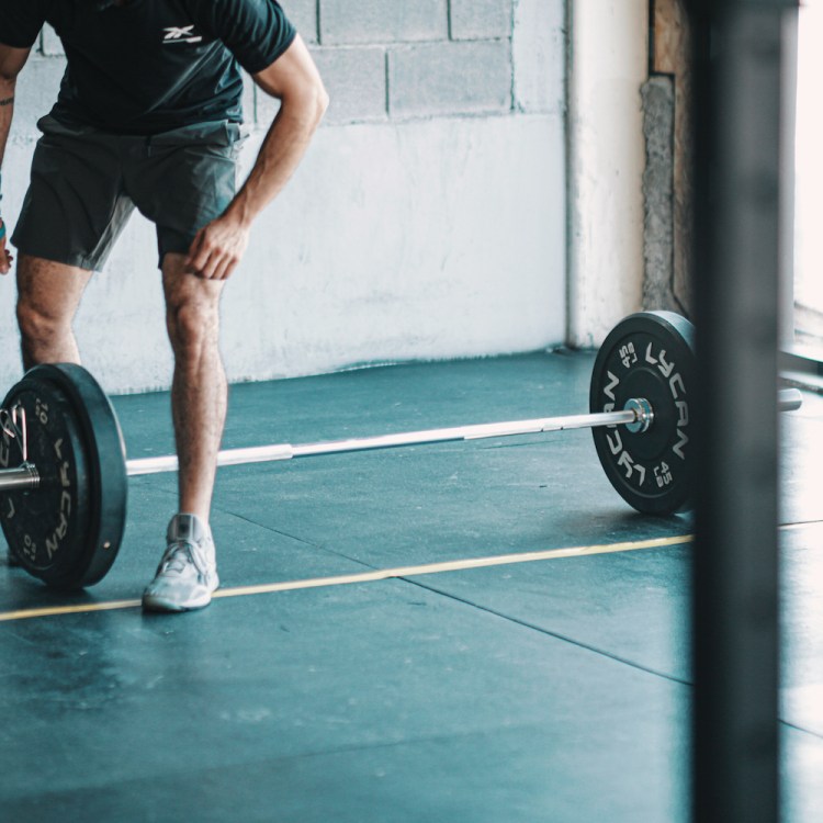 A man leaning over a barbell.