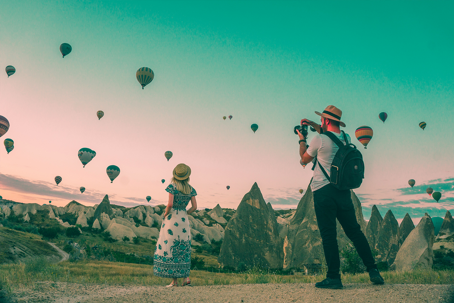 A photographer taking a picture of an influencer in front of a sky of hot air balloons