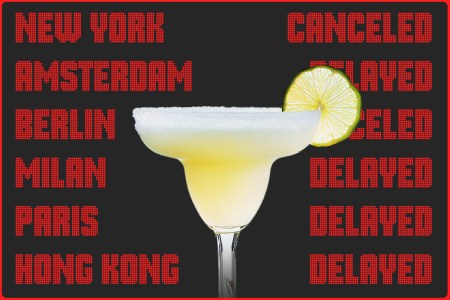 An image of a margarita cocktail in front of a departures board at an airport