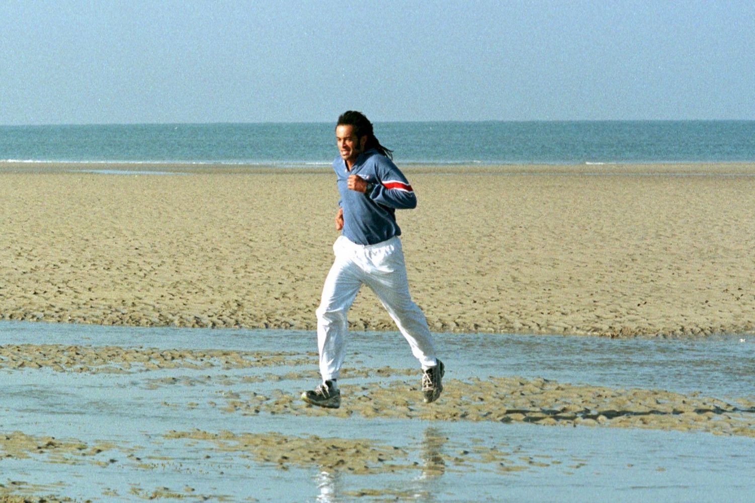 Man jogging on a beach in athletic gear, symbolizing the mental health and brain benefits of aerobic exercise.