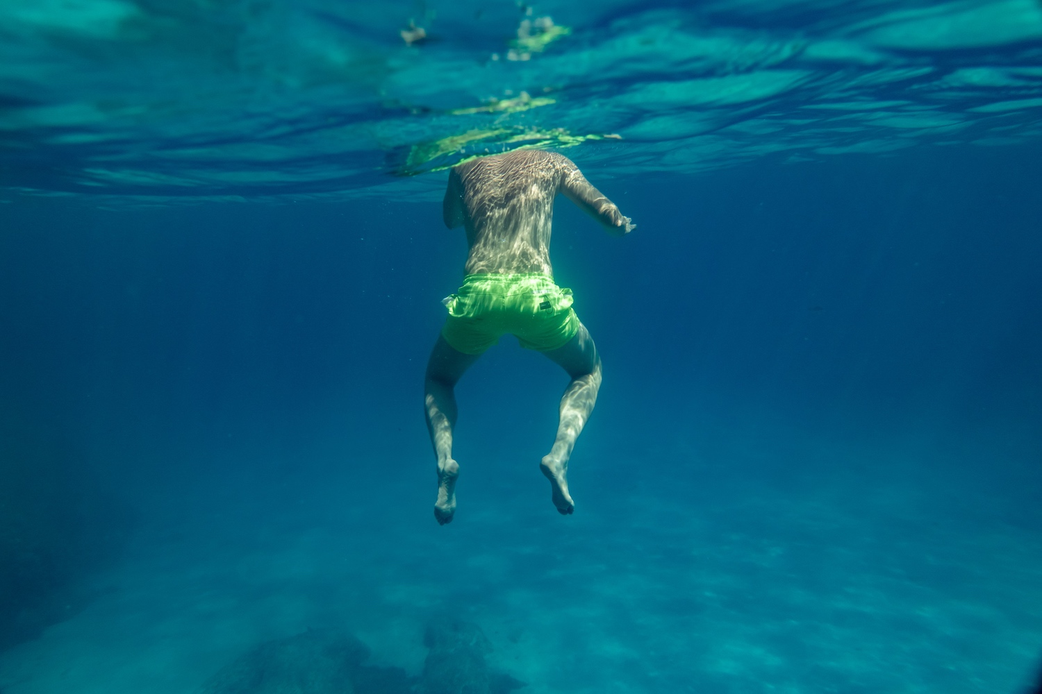 Person treading water in a lake, viewed from below the surface