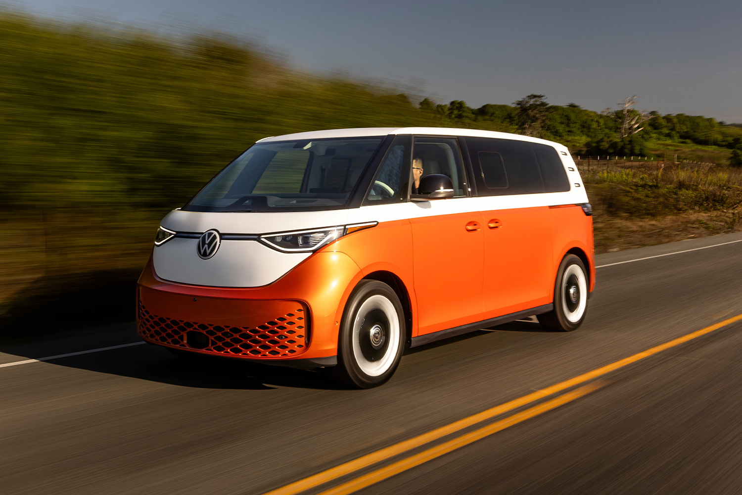 An orange Volkswagen ID. Buzz driving down the road