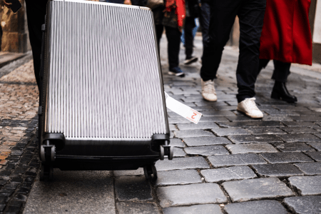 Large suitcase being dragged down cobblestone street.