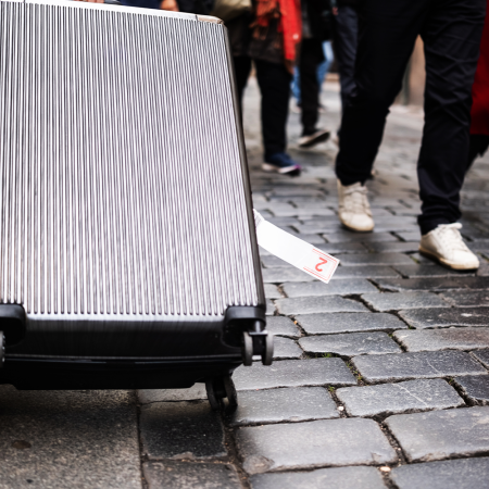 Large suitcase being dragged down cobblestone street.