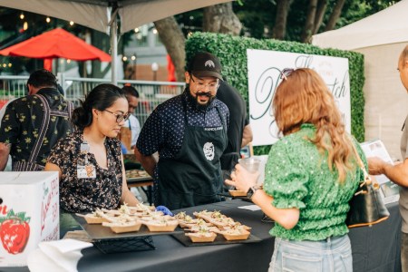a woman looking at small dishes of food at a culinary festival