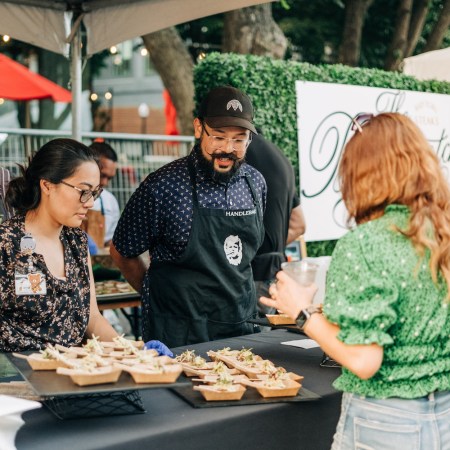 a woman looking at small dishes of food at a culinary festival