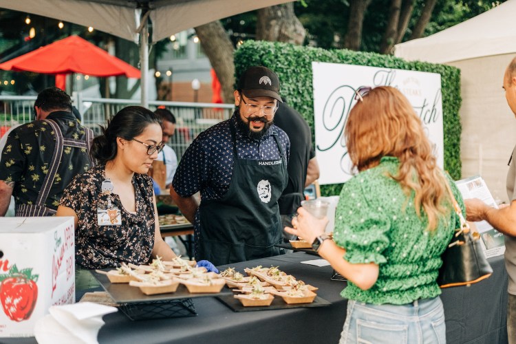 a woman looking at small dishes of food at a culinary festival