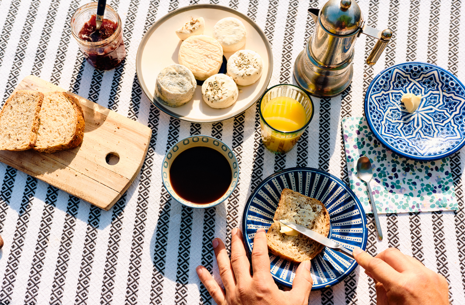 France, Nouvelle-Aquitaine, Bordeaux, man spreading butter whilst sitting for his continental breakfast