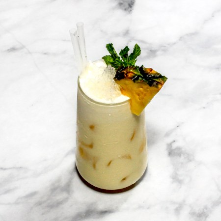 A cocktail ''Pina colada'' is sitting on a bright background