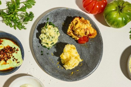 three compound butters on a grey plate on a table next to fresh produce