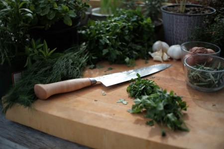 A knife on a cutting board next to different types of greens. We look at ways to get more fiber into your diet.